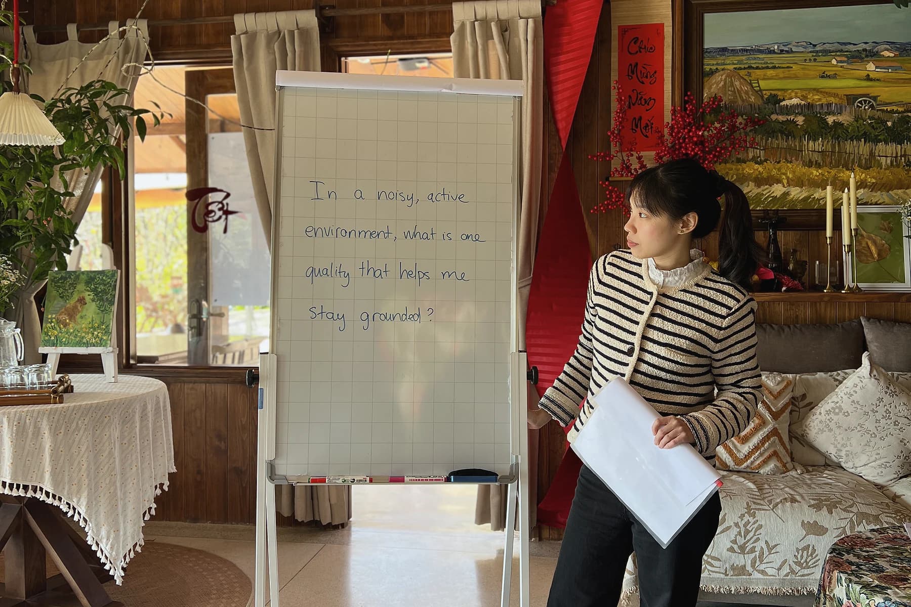 A facilitator leads a PaperFrame workshop beside a handwritten flip chart in Da Lat.